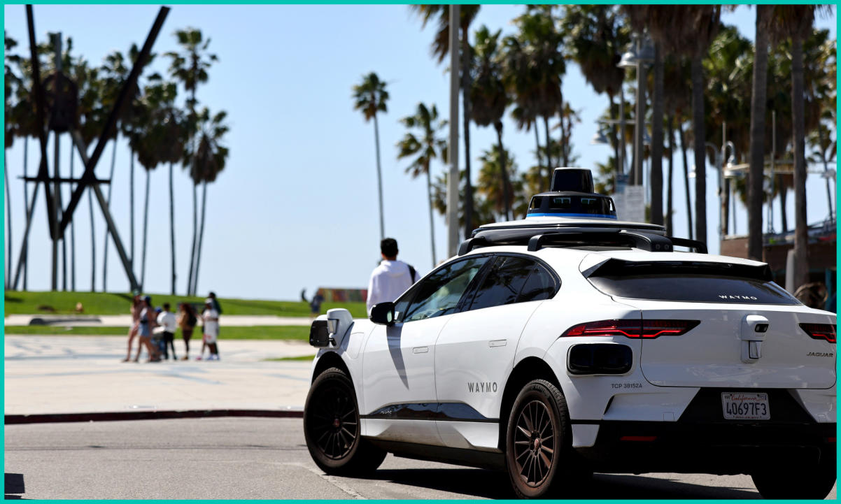 A Waymo autonomous self-driving Jaguar taxi drives along Venice Beach
