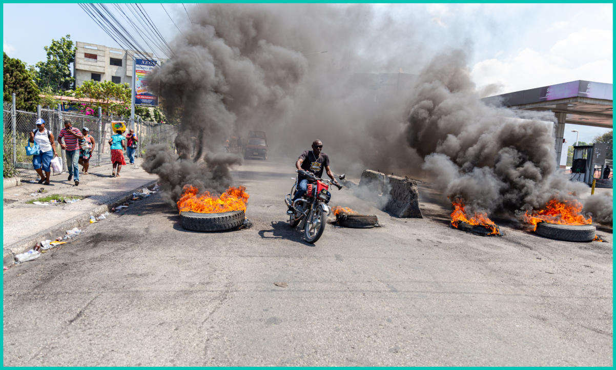 A motorcyclist passes burning tires during a demonstration against CARICOM for the decision following the resignation of Haitian Prime Minister Ariel Henry as representatives of the Caribbean Community