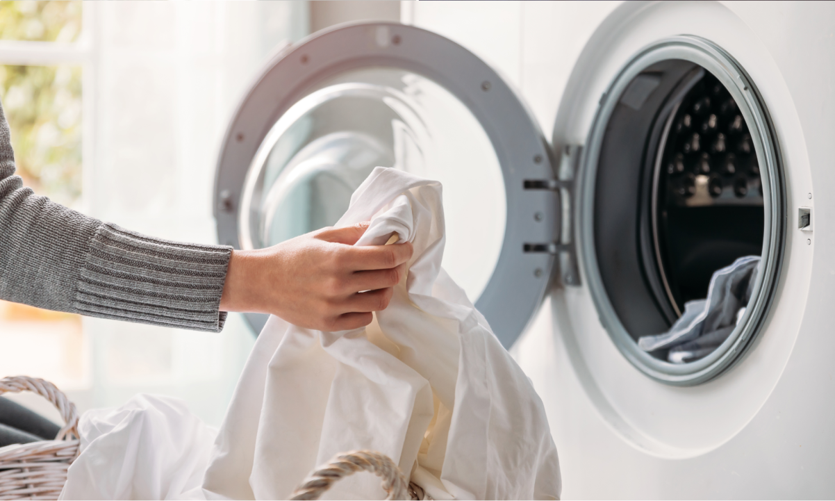 Close up of female hands dropping dirty laundry in the washing machine