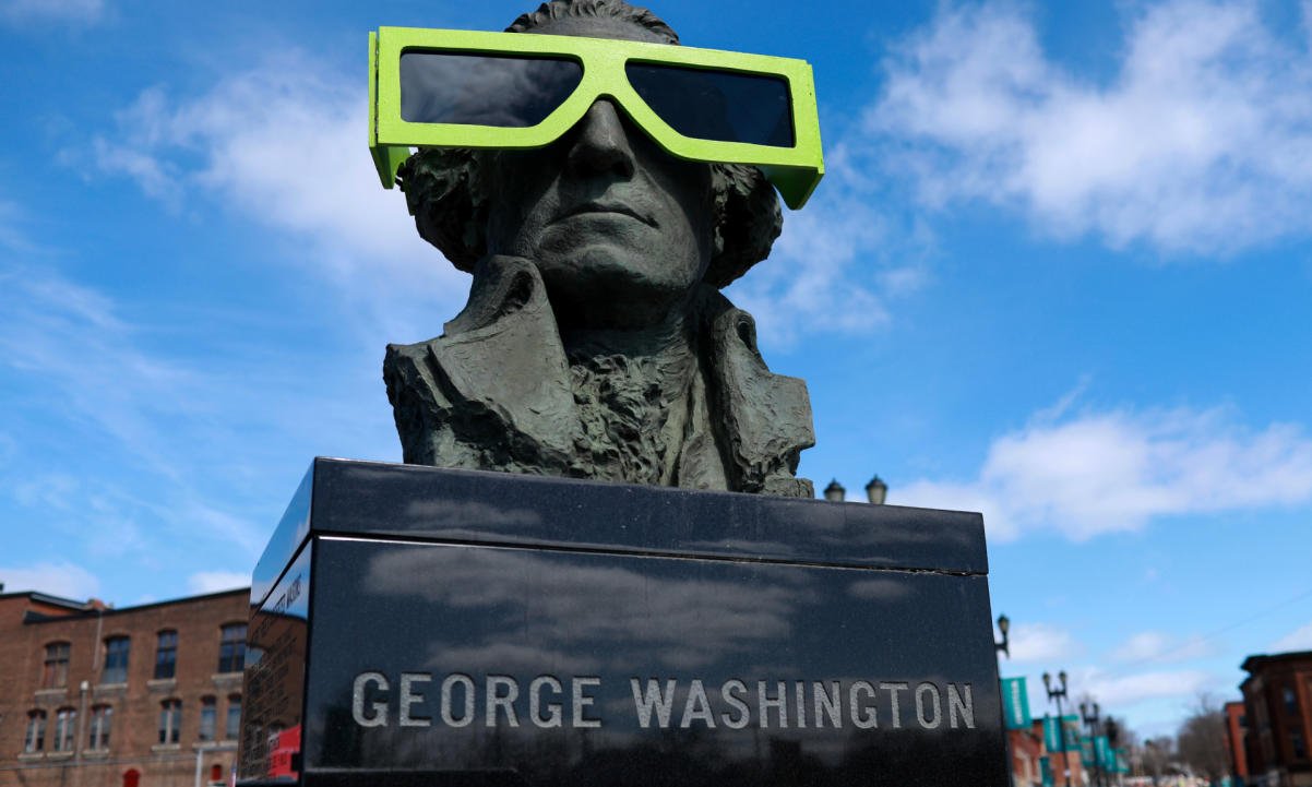 Eclipse glasses are worn by a statue of George Washington